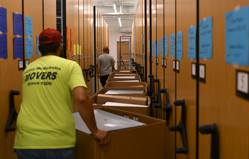 Dan Hostetler, left, and Dave Rodman move boxes between empty archive shelves